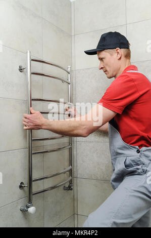 Klempner installiert Handtuchwärmer an der Wand im Bad. Stockfoto
