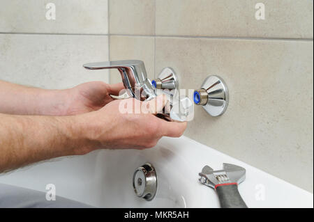 Klempner Holding eine Badewanne Armatur und installiert es. Stockfoto