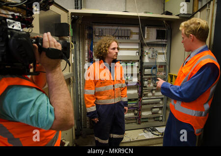 Ein Kameramann filmen Arbeitnehmer im Schaltraum einer großen Fabrik Stockfoto