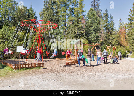 STRBSKE PLESO, SLOWAKEI - Oktober 01, 2017: Leute mit Kindern besuchen, Spielplatz und manuelle Karussell auf dem strbske Seeufer. Es ist ein beliebter Ski, Tou Stockfoto