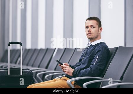 Mann mit dem Flugzeug reisen. Junge Passagier im Terminal warten. Stockfoto