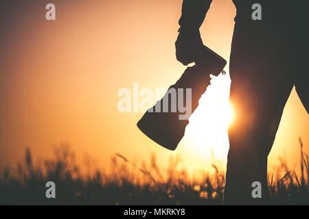 Safari Outdoor Fotograf bei Sonnenuntergang. Silhouette der Männer halten Digitale Kamera in der Hand mit großen Teleobjektiv für die bessere Wildlife Nahaufnahmen. Stockfoto