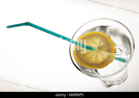 Ein Glas frisches Trinkwasser und ein Kalk. Mineralwasser, Kalk und Stroh auf weißem Hintergrund Stockfoto