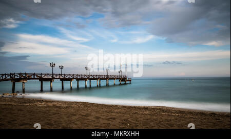 Lange Exposition von einem Strand in Marbella an der Costa del Sol in Spanien bei Sonnenuntergang im späten Frühling genommen. Stockfoto