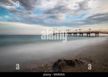 Lange Exposition von einem Strand in Marbella an der Costa del Sol in Spanien bei Sonnenuntergang im späten Frühling genommen. Stockfoto