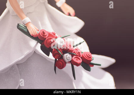 Hand eine Puppe Braut mit einem Blumenstrauß. Dekorative Hochzeit Schmuck Hintergrund. Handgefertigte Puppe trägt ein weißes Kleid aus EVA-Schaum. Stockfoto
