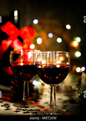 Urlaub Hintergrund mit Gläser Rotwein, Rotwein und Weihnachten Ornamente auf hölzernen Tisch Stockfoto