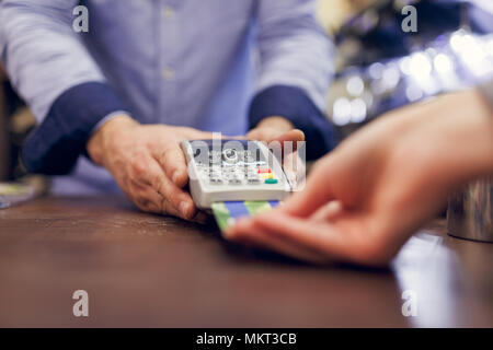 Bild der männlichen Verkäufer mit Stift in der Hand und die Käufer mit der Kreditkarte. Stockfoto