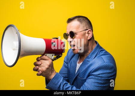 Reifen Geschäftsmann in Sonnenbrille sprechen mit Lautsprecher auf gelbem Hintergrund Stockfoto