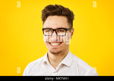 Lustig junge Mann mit weißem Hemd und Brille auf Gelb Hintergrund posiert Stockfoto