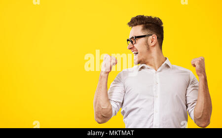 Jungen gutaussehenden Mann in Brillen holding hands up mit Erfolg auf gelben Hintergrund aufgeregt. Stockfoto