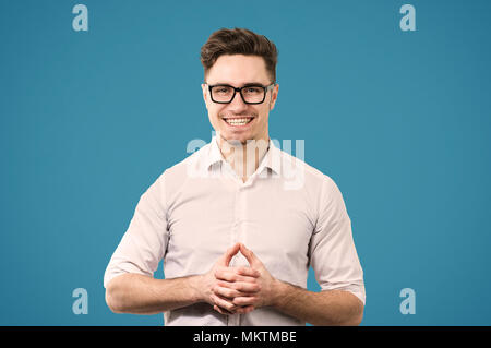 Glückliche junge Mann in Brillen und Shirt auf Kamera, Hände halten zusammen mit Erfolg aufgeregt lächelnd. Stockfoto