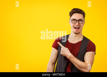 Junge stilvolle hipster Mann in Gläser glücklich zeigen auf orange gelb hinterlegt Stockfoto