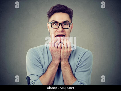 Junger Mann in Gläser, die panikattacke und Suchen mit Angst an der Kamera auf grauem Hintergrund. Stockfoto