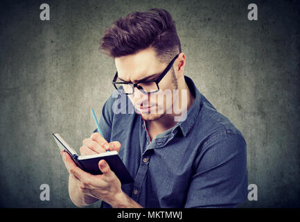 Jungen gutaussehenden Mann auf die Planung und Organisation von Leben Notizen in Pad konzentriert. Stockfoto
