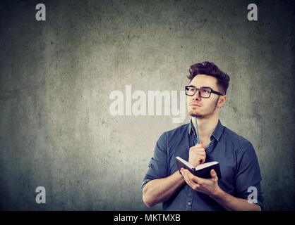 Schöner Mann in Gläsern Notizblock mit Stift und gründlich Denken auf Neuer Plan. Stockfoto
