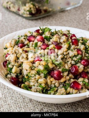 Weizen Salat mit Granatapfel in weiße Schüssel. Ökologische Lebensmittel Stockfoto
