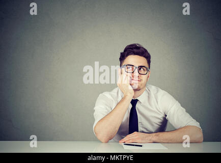 Junge Betrachtung Mann vorstellen, statt Sitzen am Tisch im Amt. Stockfoto