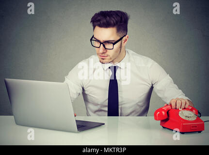 Jungen gutaussehenden Mann in Gläsern mit Laptop und Arbeiten in Call Center die Hand am Telefon. Stockfoto