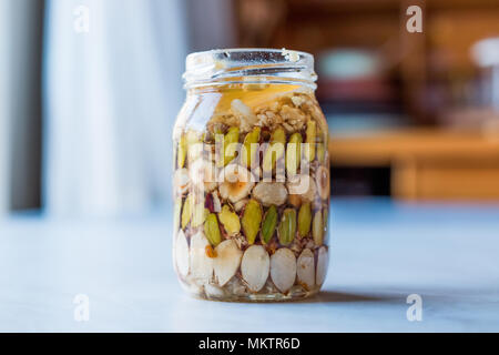 Honig mit Nüssen, Mandeln und Erdnuss Krokant Dessert im Glas. Ökologische Lebensmittel. Stockfoto