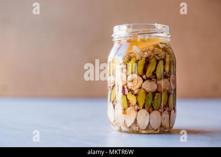 Honig mit Nüssen, Mandeln und Erdnuss Krokant Dessert im Glas. Ökologische Lebensmittel. Stockfoto