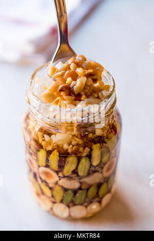 Honig mit Nüssen, Mandeln und Erdnuss Krokant Dessert im Glas. Ökologische Lebensmittel. Stockfoto