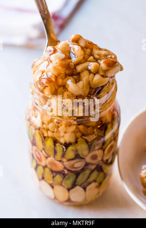 Honig mit Nüssen, Mandeln und Erdnuss Krokant Dessert im Glas. Ökologische Lebensmittel. Stockfoto