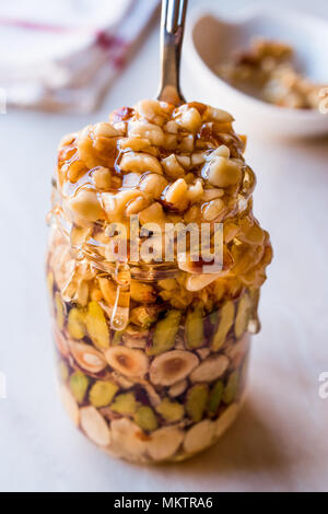 Honig mit Nüssen, Mandeln und Erdnuss Krokant Dessert im Glas. Ökologische Lebensmittel. Stockfoto