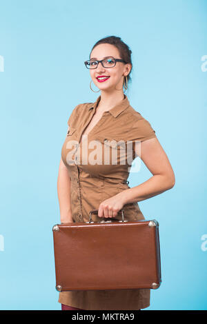 Portrait von Begeistert junge Frau mit einem Koffer auf blauem Hintergrund, Reisen, Urlaub und Ferien Konzept isoliert. Stockfoto