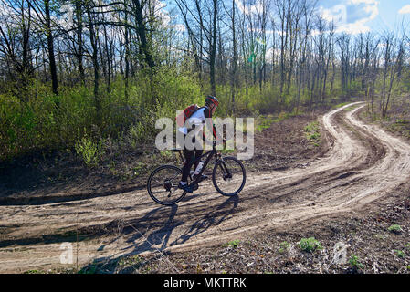 Ein junger Mann im Sport Kleidung Fahrten mit dem Fahrrad auf der Straße in den Wald. Stockfoto