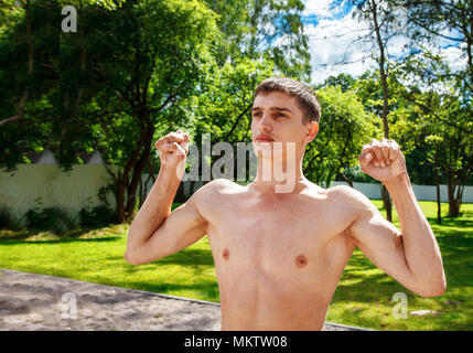 Junger Mann, gymnastischen Übungen im Hof auf sonnigen Sommertag Stockfoto