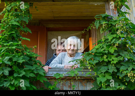 Ältere Frau mit ihrer erwachsenen Tochter auf der Veranda eines Bauernhauses. Stockfoto