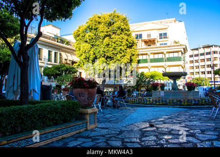 Platz. Ein kleiner Platz mit Restaurants und einem Brunnen in Estepona. Provinz Malaga, Andalusien, Spanien. Bild genommen - 4. Mai 2018. Stockfoto