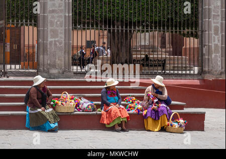 Drei Sierra Otomi indische Frauen in streuen Hüte verkauft die farbenfrohen handgefertigten Kinder Puppen in San Miguel de Allende in Mexiko, Stockfoto