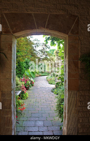 Mit Blick auf einen Garten Weg durch eine gewölbte Stein Tür Stockfoto