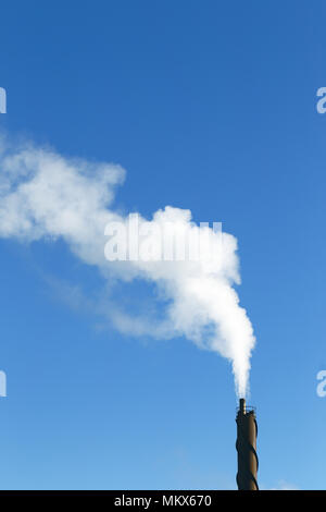 Rauch aus einem Schornstein an einem klaren blauen Himmel. Stockfoto
