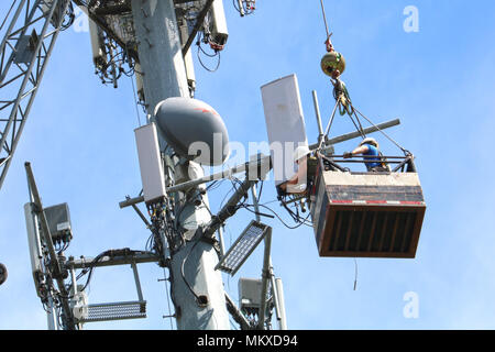 Zwei Männer, die in der Luft verschoben werden über ein Kabel beim Arbeiten auf ein Handy Turm in Ferndale, Washington, USA. Stockfoto