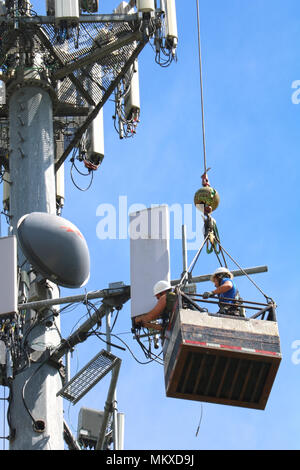 Zwei Männer, die in der Luft verschoben werden über ein Kabel beim Arbeiten auf ein Handy Turm in Ferndale, Washington, USA. Stockfoto