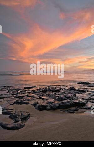 Schönen Sonnenaufgang über einen entfernten Leuchtturm von Kilauea aus anini Punkt entlang der North Shore auf Hawaii Insel Kauai. Stockfoto