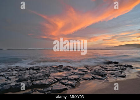 Schönen Sonnenaufgang über einen entfernten Leuchtturm von Kilauea aus anini Punkt entlang der North Shore auf Hawaii Insel Kauai. Stockfoto