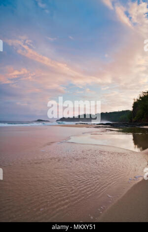 Schönen Sonnenaufgang über geheime Strand und einem entfernten Leuchtturm von Kilauea entlang dem North Shore auf Hawaii Insel Kauai. Stockfoto