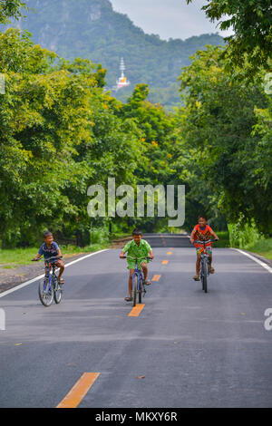 Lopburi, Thailand - 21. Juli 2013: drei Jungen mit verschiedenen farbigen shirts Fahrrad über die ländliche Straße in Lopburi, Thailand Stockfoto