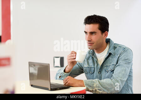 Gut aussehenden Mann tragen Jeanshemd sitzen in einem Café. Blaue Augen Kerl mit legere Kleidung. Stockfoto
