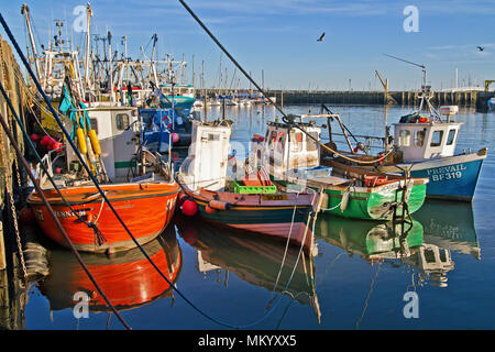 Eine Gruppe von kleinen Fischereifahrzeugen beleuchtet durch die Abendsonne am Liegeplatz im Hafen von Scarborough. Stockfoto