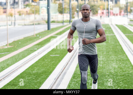 Schwarzer Mann laufen und Hören von Musik im städtischen Hintergrund. Stattliche männliche tun Training im Freien. Stockfoto