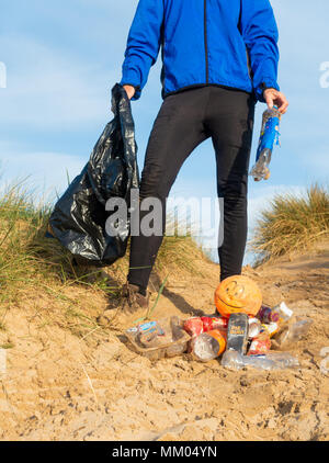 Ein Jogger Plogging (Abholung Wurf beim Joggen) auf seinen Morgen durch Sanddünen. DE Stockfoto