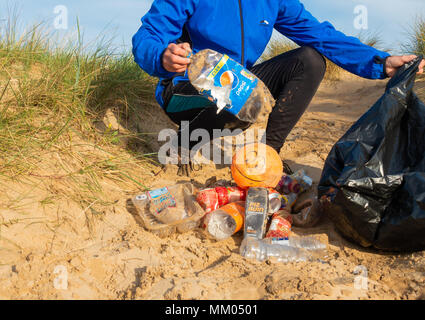 Ein Jogger Plogging (Abholung Wurf beim Joggen) auf seinen Morgen durch Sanddünen. DE Stockfoto