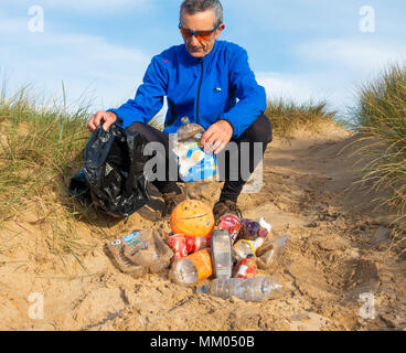 Ein Jogger Plogging (Abholung Wurf beim Joggen) auf seinen Morgen durch Sanddünen. DE Stockfoto