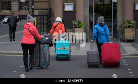 Glasgow, Schottland, Großbritannien 9. Mai. UK Wetter: Frauen Frauen mit Koffer Taschen Kreuzung Straße George Square im Herzen der Stadt bietet wenig für den Touristen so stumpf nasses Wetter zieht nach dem heißen Bank Urlaub.. Gerard Fähre / alamy Nachrichten Stockfoto