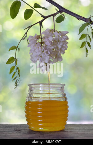 Krug Honig mit Blumen von Akazienholz auf Tisch Stockfoto